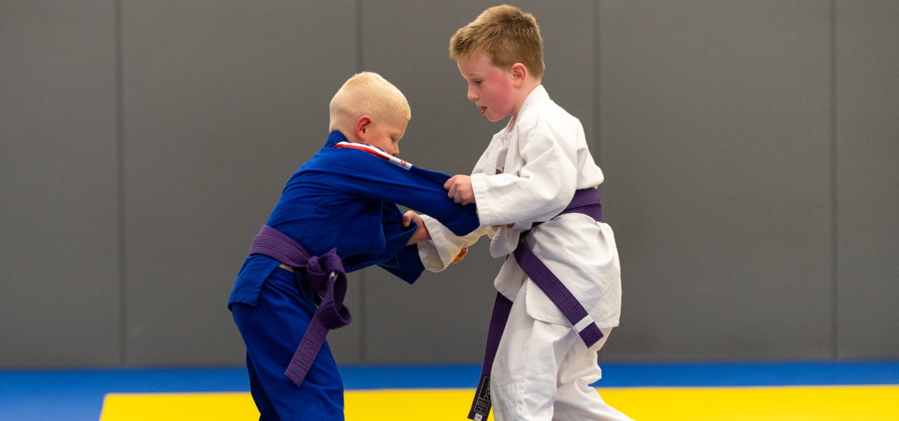 Two young judokas grapple on a mat.