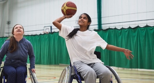 A young female wheelchair basketballer takes a shot.