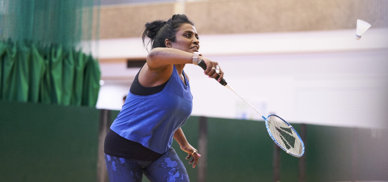 A woman playing badminton in a sports hall.