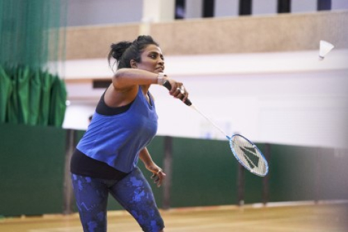 A woman playing badminton in a sports hall.