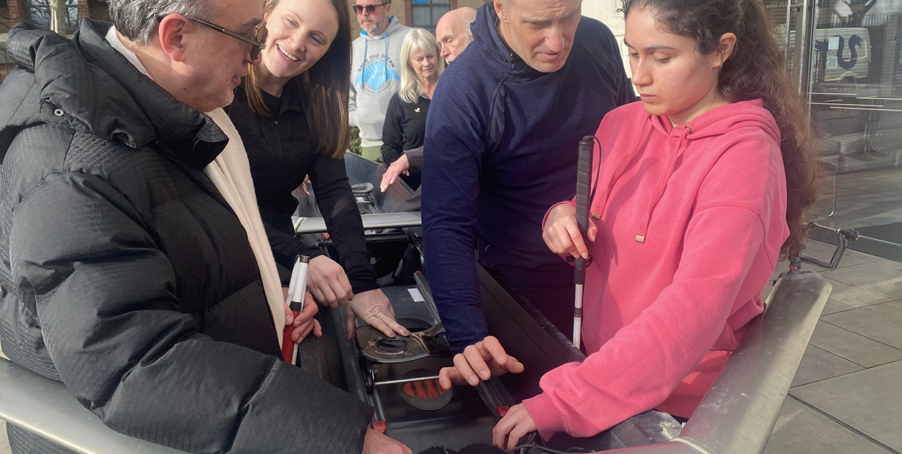 A blind girl and a blind man touch a boat during a rowing training session in the street.