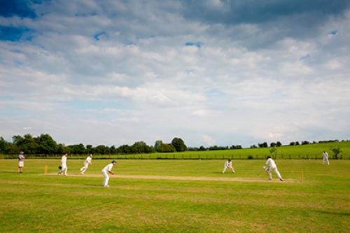 A game of cricket is played on a community playing field