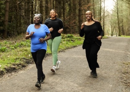 Three women stride through a forest