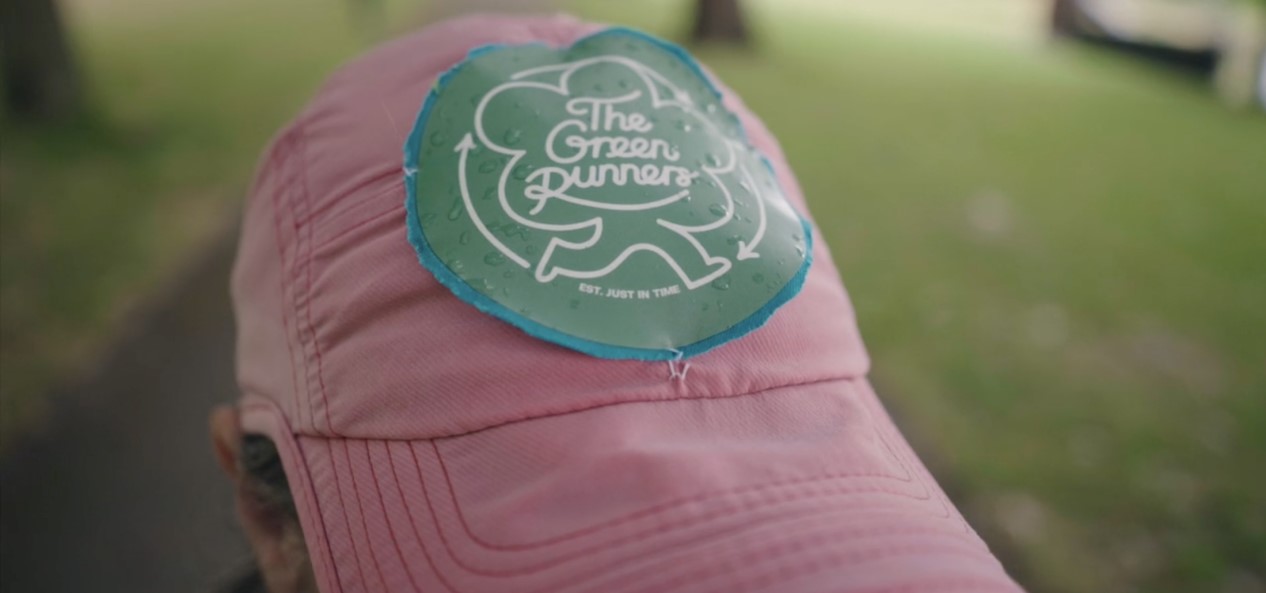 Close-up of a baseball cap on a man's head, featuring the logo of The Green Runners.