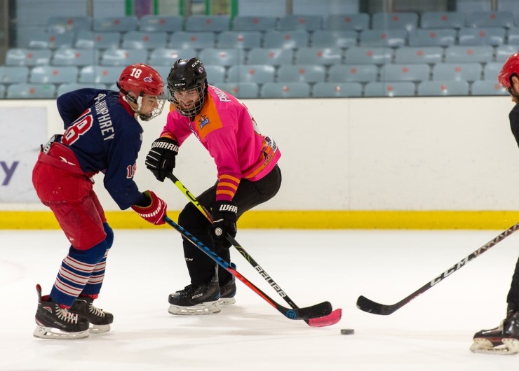 Three ice hockey players compete for the puck.