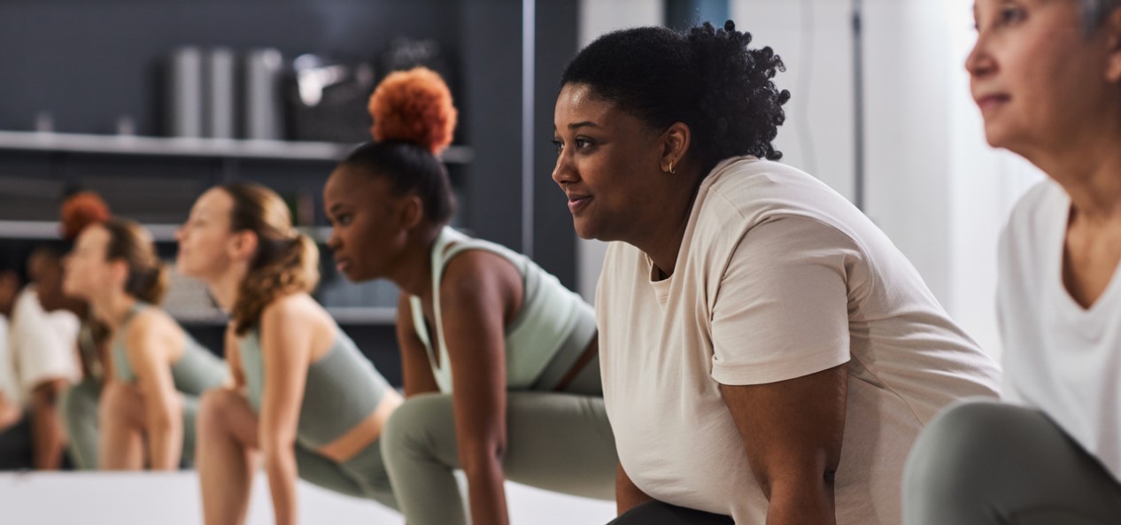 A row of women lunging with blocks in a fitness class.