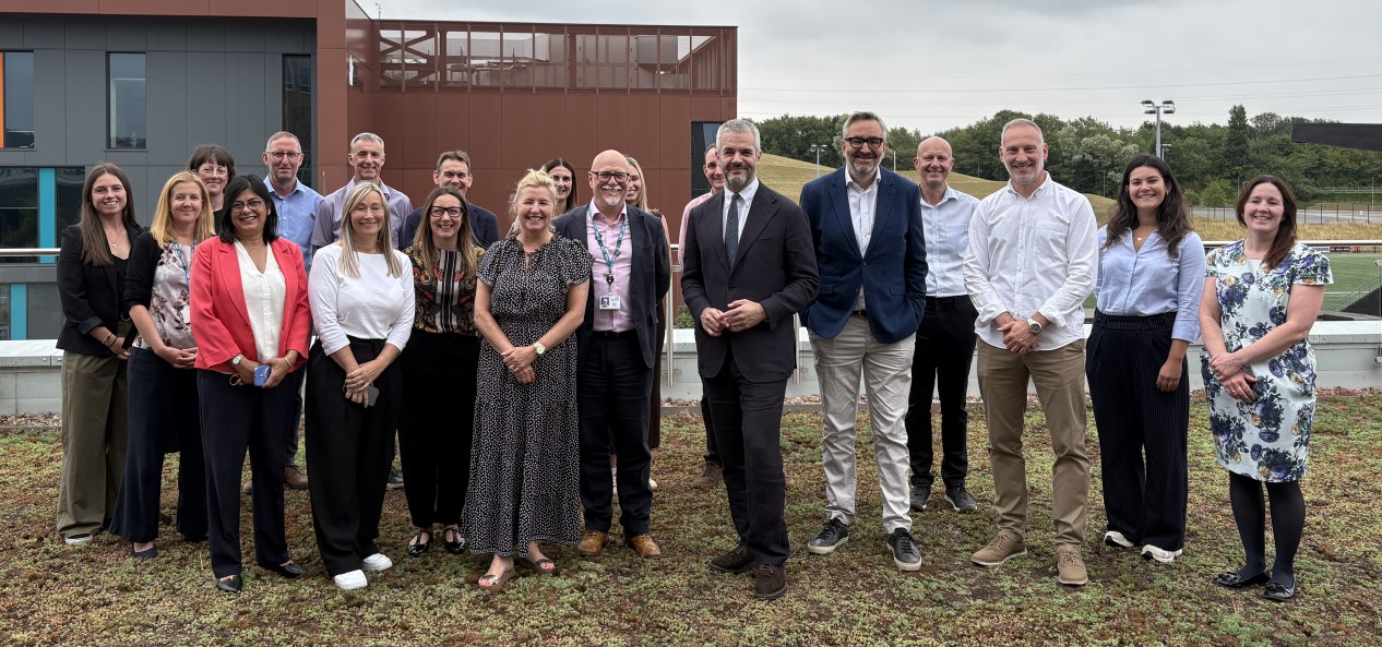 A group of people including Sport England chief executive Tim Hollingsworth, South Yorkshire mayor Oliver Coppard, and South Yorkshire Integrated Care Board CEO Gavin Boyle pose for a photo on a grassy area after the signing of a memorandum of understanding.