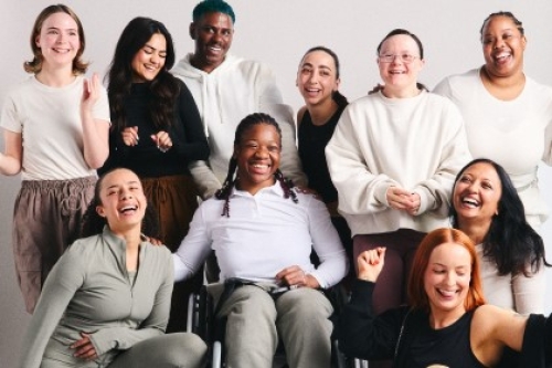 A group of women with a variety of characteristics smile for a posed shot.